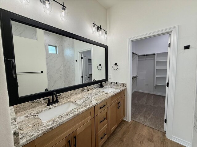 full bath featuring a walk in closet, wood finished floors, a sink, and double vanity