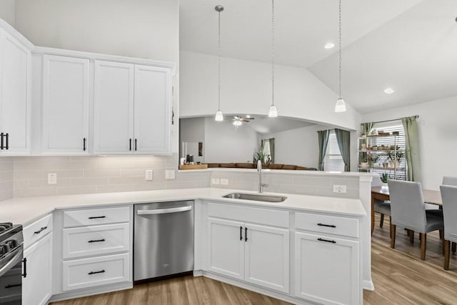 185 Dogvane Cir, Kyle, TX 78640 - kitchen with stainless steel dishwasher, a sink, a peninsula, light wood-type flooring, and vaulted ceiling