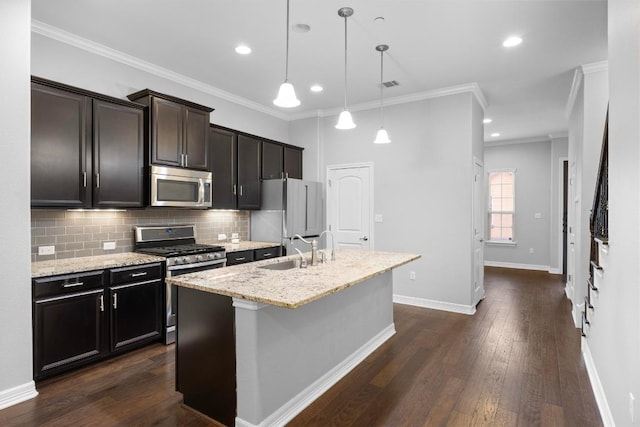 kitchen featuring stainless steel appliances, backsplash, ornamental molding, a sink, and a center island with sink