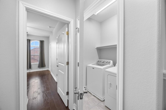washroom with hardwood / wood-style flooring, separate washer and dryer, baseboards, and laundry area
