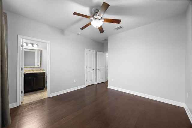 unfurnished bedroom with ensuite bathroom, baseboards, visible vents, a ceiling fan, and wood finished floors