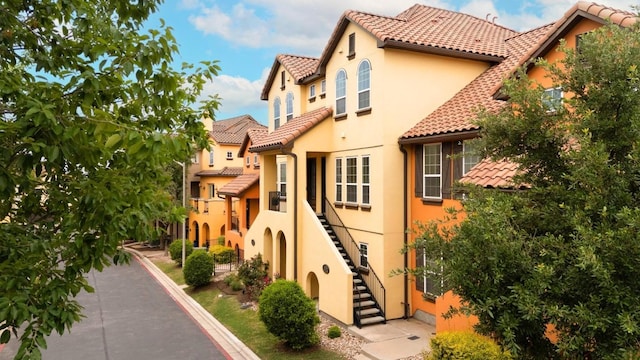 view of side of home featuring a tile roof, stairs, and stucco siding