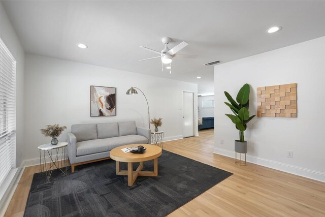 living room featuring ceiling fan, baseboards, and wood finished floors