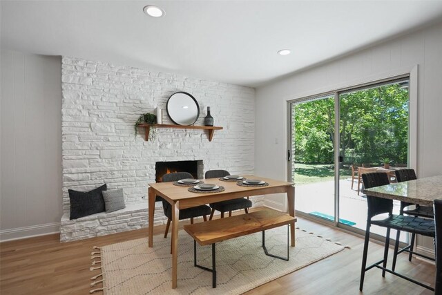 dining room featuring a fireplace, wood finished floors, baseboards, and recessed lighting