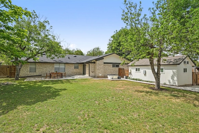 rear view of house with brick siding, fence, a yard, and a patio
