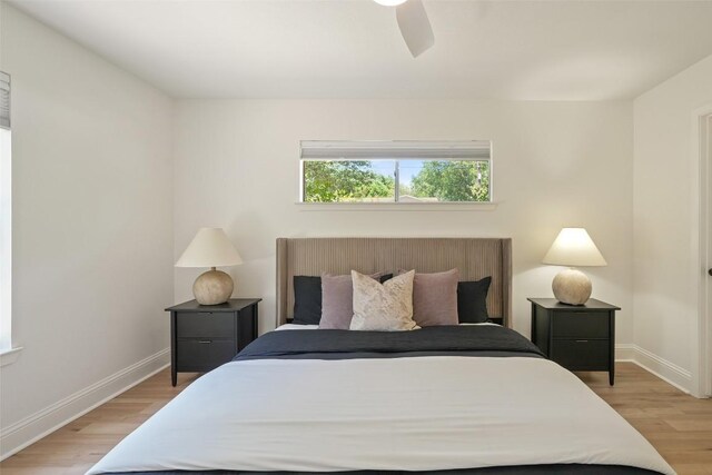 bedroom with light wood-style flooring, a ceiling fan, and baseboards