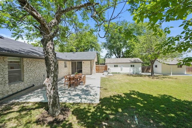 rear view of property featuring a lawn, a patio, an outbuilding, and fence
