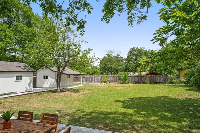 view of yard featuring a patio area, a fenced backyard, and an outbuilding