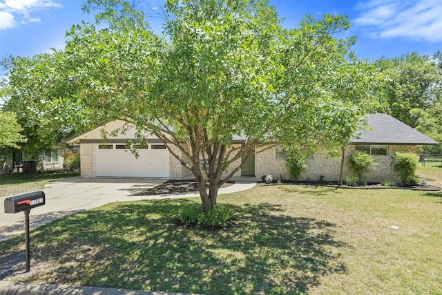 view of property hidden behind natural elements featuring a front lawn, driveway, brick siding, and a garage