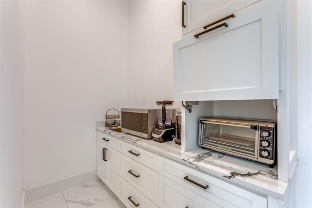 interior details with stainless steel microwave, baseboards, and a toaster