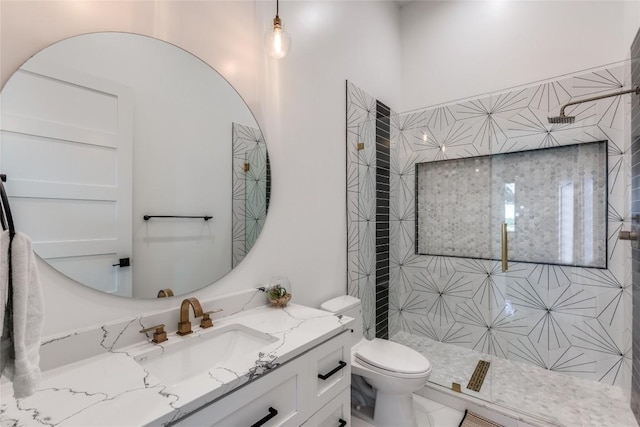 full bathroom featuring a tile shower, toilet, and vanity
