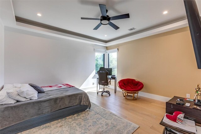 bedroom with recessed lighting, a raised ceiling, wood finished floors, and visible vents
