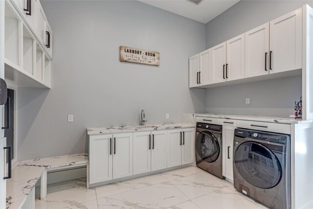 laundry room featuring washing machine and dryer, cabinet space, marble finish floor, and a sink