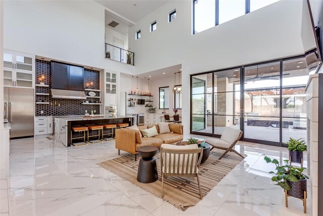 living room featuring visible vents, plenty of natural light, marble finish floor, and a high ceiling