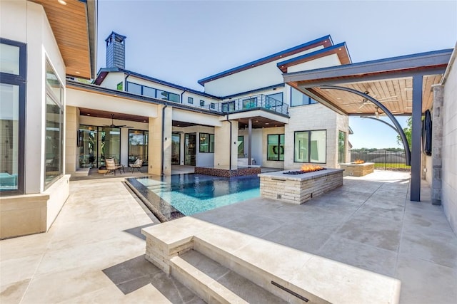 view of patio with a balcony, fence, a fenced in pool, and an outdoor fire pit