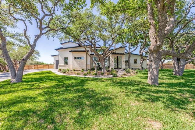 view of front of property with fence, a front lawn, and stucco siding
