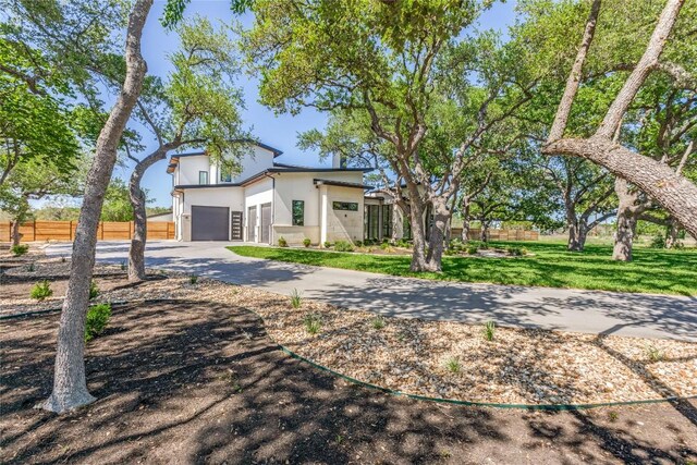 view of front of property featuring concrete driveway, a front lawn, fence, a garage, and stucco siding