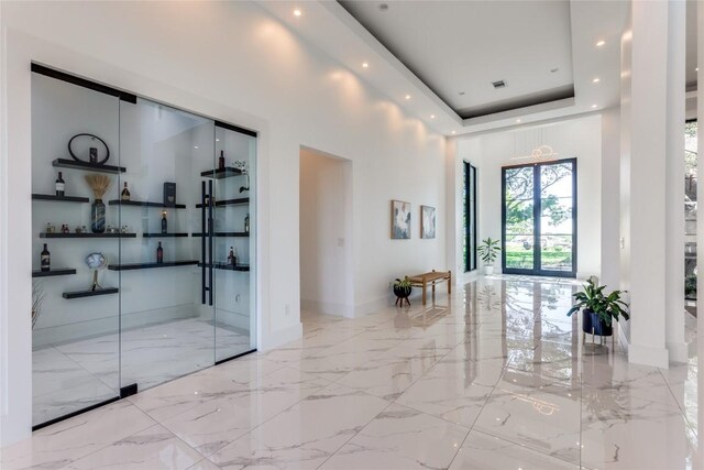 corridor with marble finish floor, a raised ceiling, baseboards, visible vents, and recessed lighting
