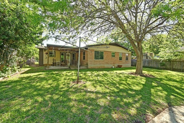 4722 Frontier Trl, Austin, TX 78745 - back of house featuring a lawn, a patio, brick siding, and a fenced backyard