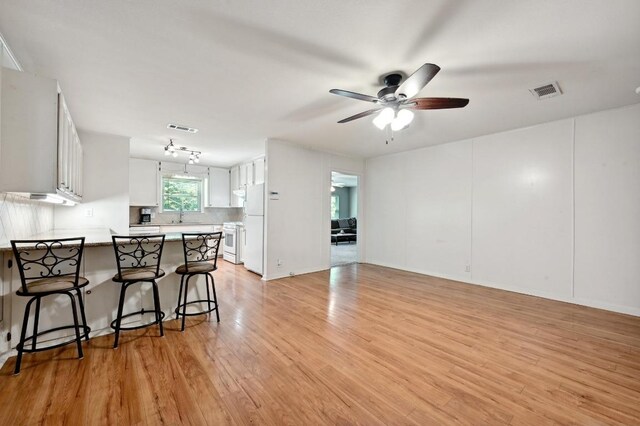4722 Frontier Trl, Austin, TX 78745 - kitchen with ceiling fan, white appliances, light wood-style flooring, a peninsula, and visible vents