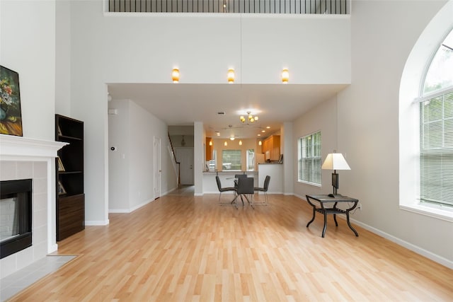 3817 E Newland Dr, Round Rock, TX 78681 - living area with light wood-style floors, healthy amount of natural light, baseboards, a tiled fireplace, and a high ceiling