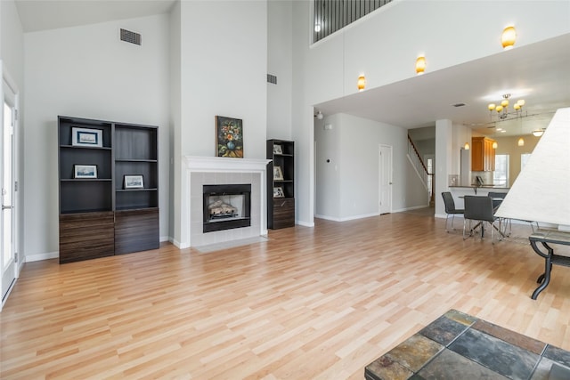 3817 E Newland Dr, Round Rock, TX 78681 - living area with a towering ceiling, stairs, light wood-type flooring, baseboards, and a tile fireplace