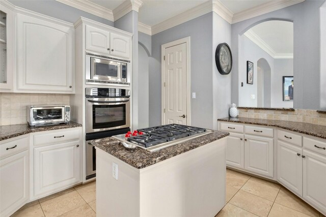 4101 Top Of Texas Trl, Austin, TX 78735 - kitchen with stainless steel appliances, arched walkways, backsplash, crown molding, and light tile patterned floors