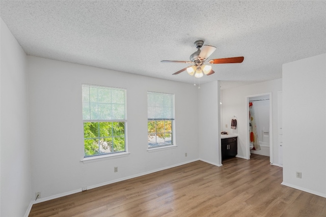 unfurnished living room featuring baseboards, a ceiling fan, a textured ceiling, and light wood-type flooring