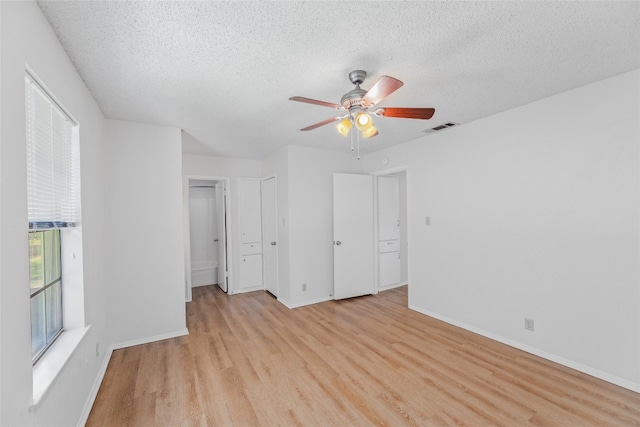 unfurnished bedroom featuring baseboards, a textured ceiling, visible vents, and light wood-style flooring
