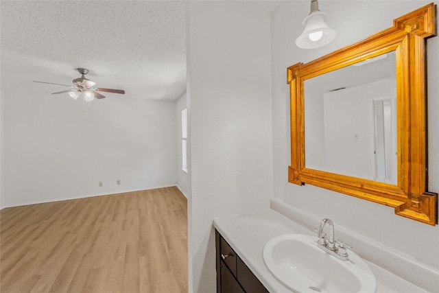 bathroom with wood finished floors, a textured ceiling, vanity, and ceiling fan