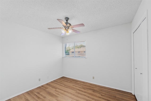 unfurnished bedroom with light wood-type flooring, baseboards, a textured ceiling, and a closet