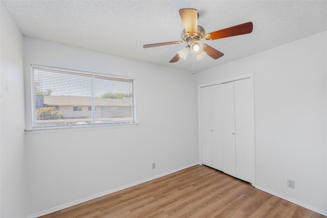 unfurnished bedroom with wood finished floors, a textured ceiling, and a closet