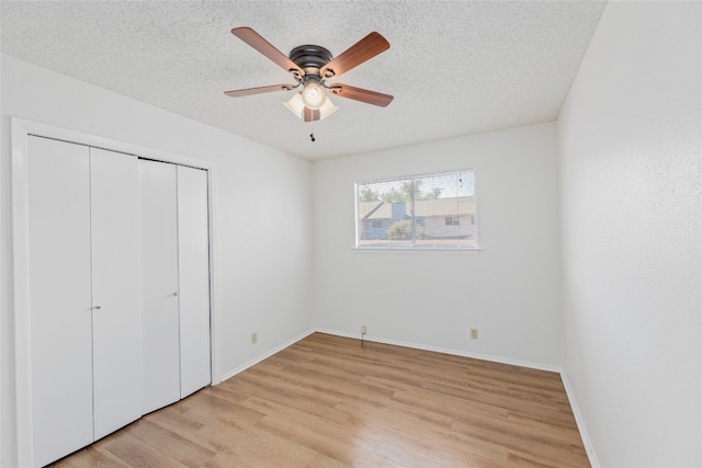 unfurnished bedroom with light wood finished floors, baseboards, a textured ceiling, and a closet