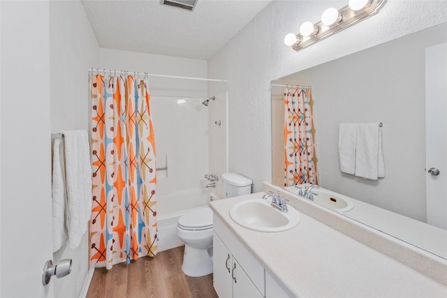 full bath with wood finished floors, a textured ceiling, vanity, shower / tub combo with curtain, and toilet