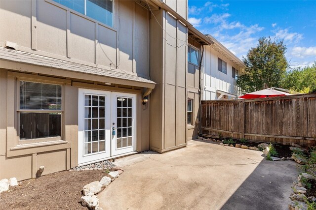 rear view of house with fence, a patio area, board and batten siding, and french doors