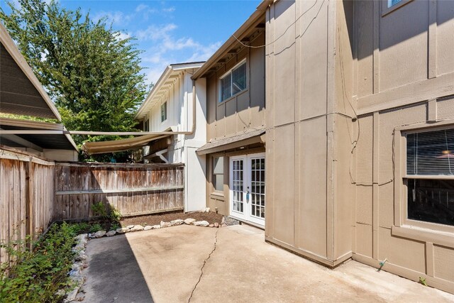 exterior space with fence, french doors, board and batten siding, and a patio