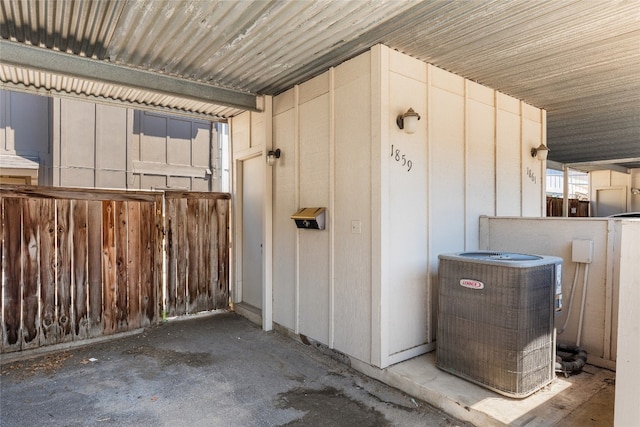 view of exterior entry with board and batten siding and central air condition unit