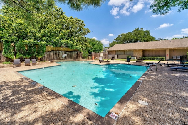 community pool with fence and a patio area