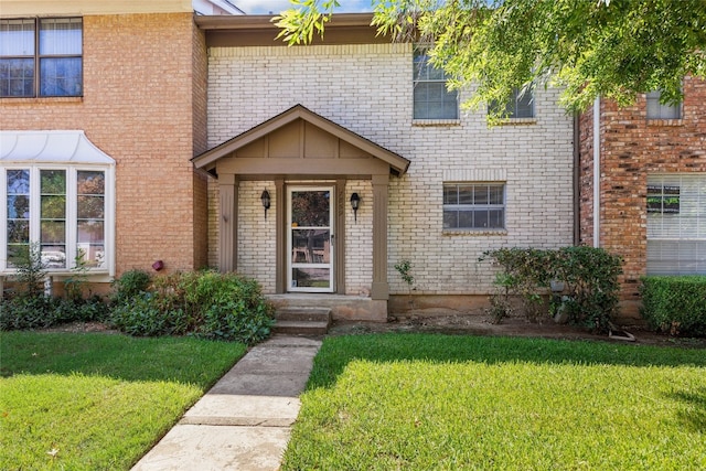 entrance to property featuring brick siding and a yard