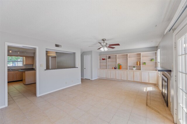 interior space featuring a textured ceiling, visible vents, a ceiling fan, and baseboards