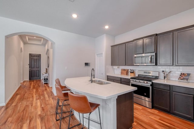 kitchen with arched walkways, tasteful backsplash, appliances with stainless steel finishes, and a sink