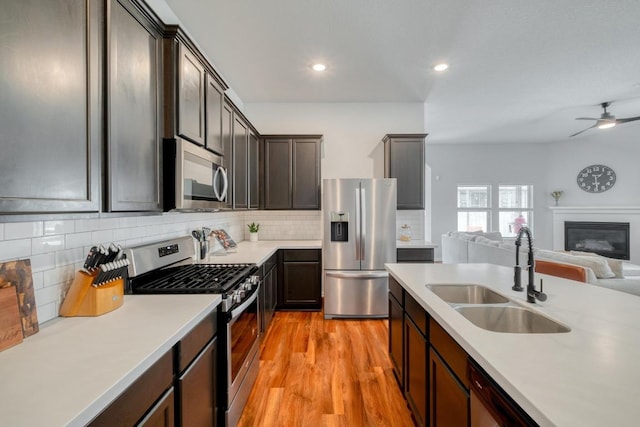 kitchen featuring a sink, light wood-type flooring, open floor plan, light countertops, and appliances with stainless steel finishes