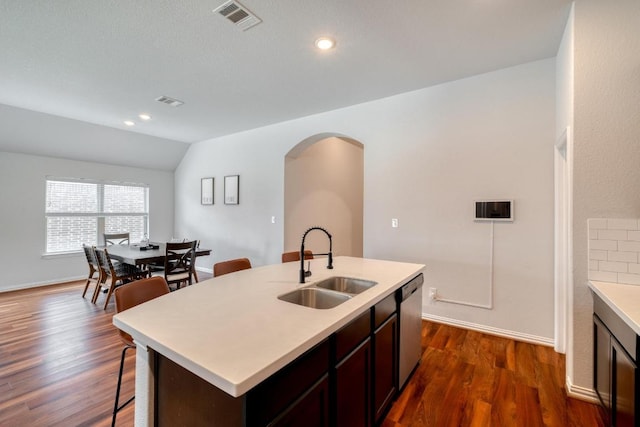 kitchen featuring light countertops, visible vents, stainless steel dishwasher, a sink, and arched walkways