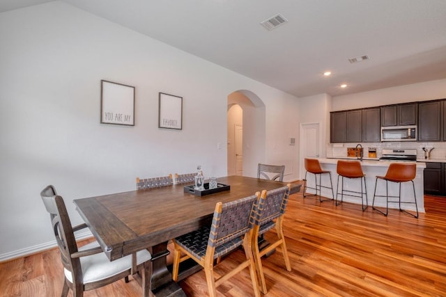 dining space featuring recessed lighting, arched walkways, visible vents, and light wood-type flooring