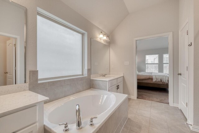 bathroom with tile patterned floors, ensuite bathroom, lofted ceiling, a garden tub, and vanity