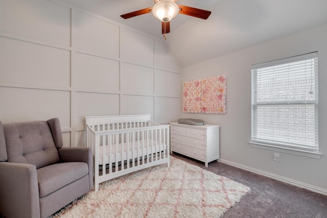 carpeted bedroom featuring a nursery area, lofted ceiling, ceiling fan, and baseboards