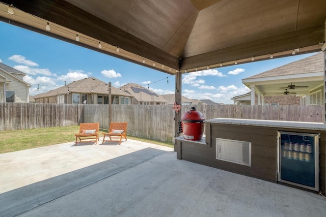 view of patio with a fenced backyard, a ceiling fan, beverage cooler, and a residential view