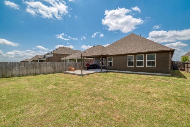 rear view of property featuring a lawn, a fenced backyard, roof with shingles, and a patio