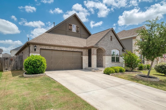 french country inspired facade featuring a front lawn, driveway, fence, brick siding, and a shingled roof