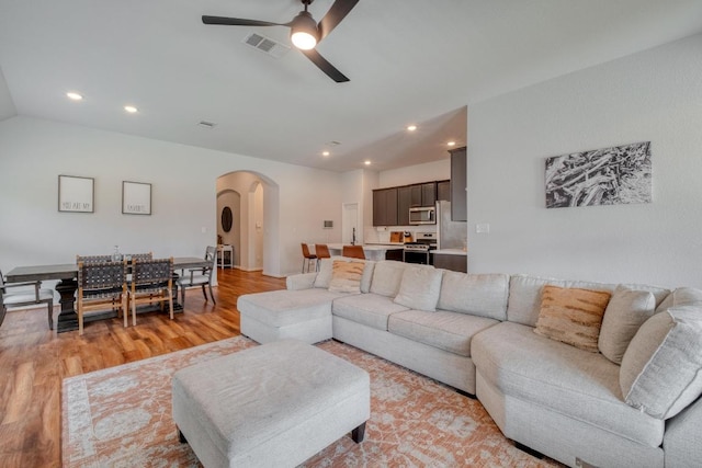living room with recessed lighting, visible vents, arched walkways, light wood-style floors, and ceiling fan